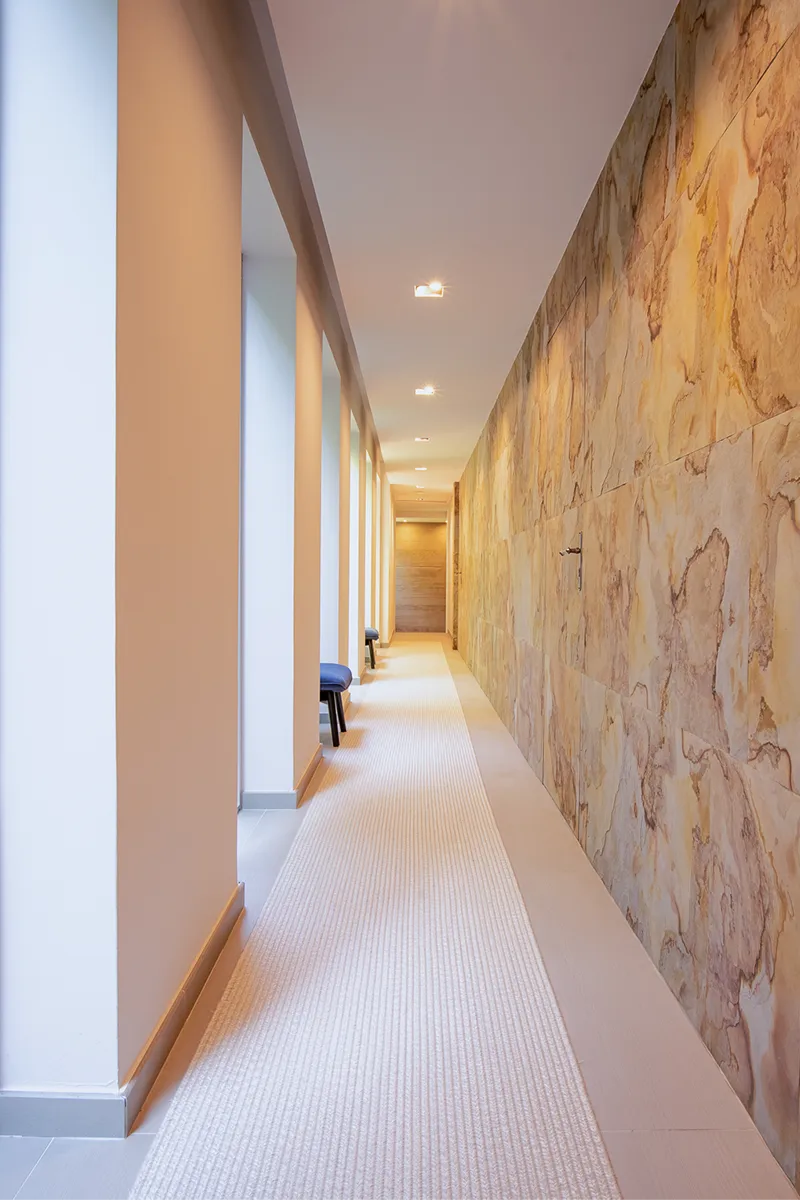 Photo d'un couloir tout en longueur dans des tons de beige, doré et crème avec des couleurs chaudes et de belles lignes architecturales prise lors d'un shooting photos et vidéos immobilières.