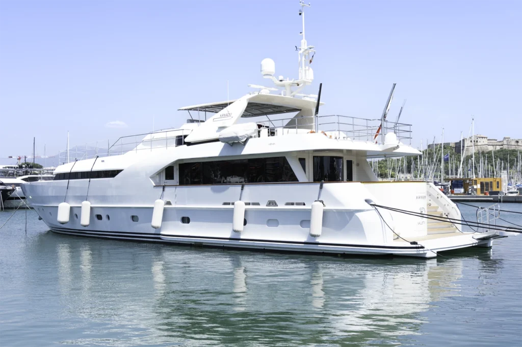 Yacht vu de l'extérieur en plan large où on voit l'entièreté du yacht blanc et bois